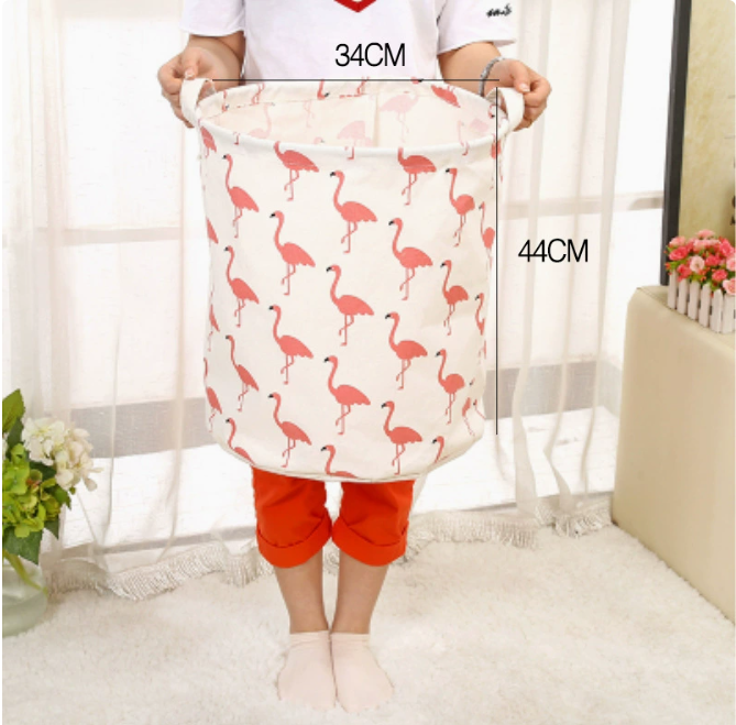 A person holds a large capacity cotton linen laundry basket featuring pink flamingo patterns, measuring 34CM by 44CM, by Pure
