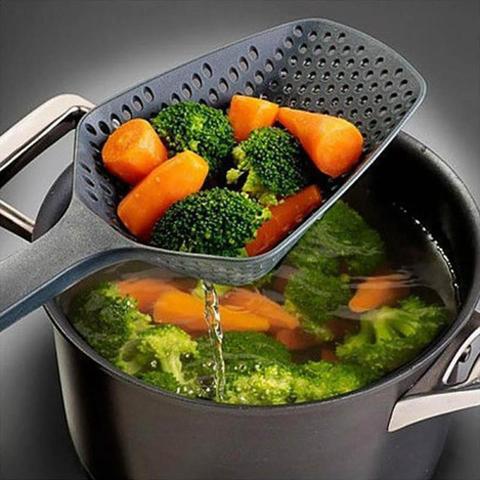 A plastic water strainer spatula lifting vibrant broccoli and carrots from a pot by PureAura.