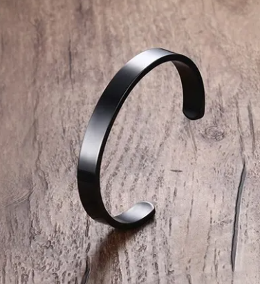 Sleek black Titanium Steel Men's Bracelet showcased on a rustic wooden surface by PureAura.