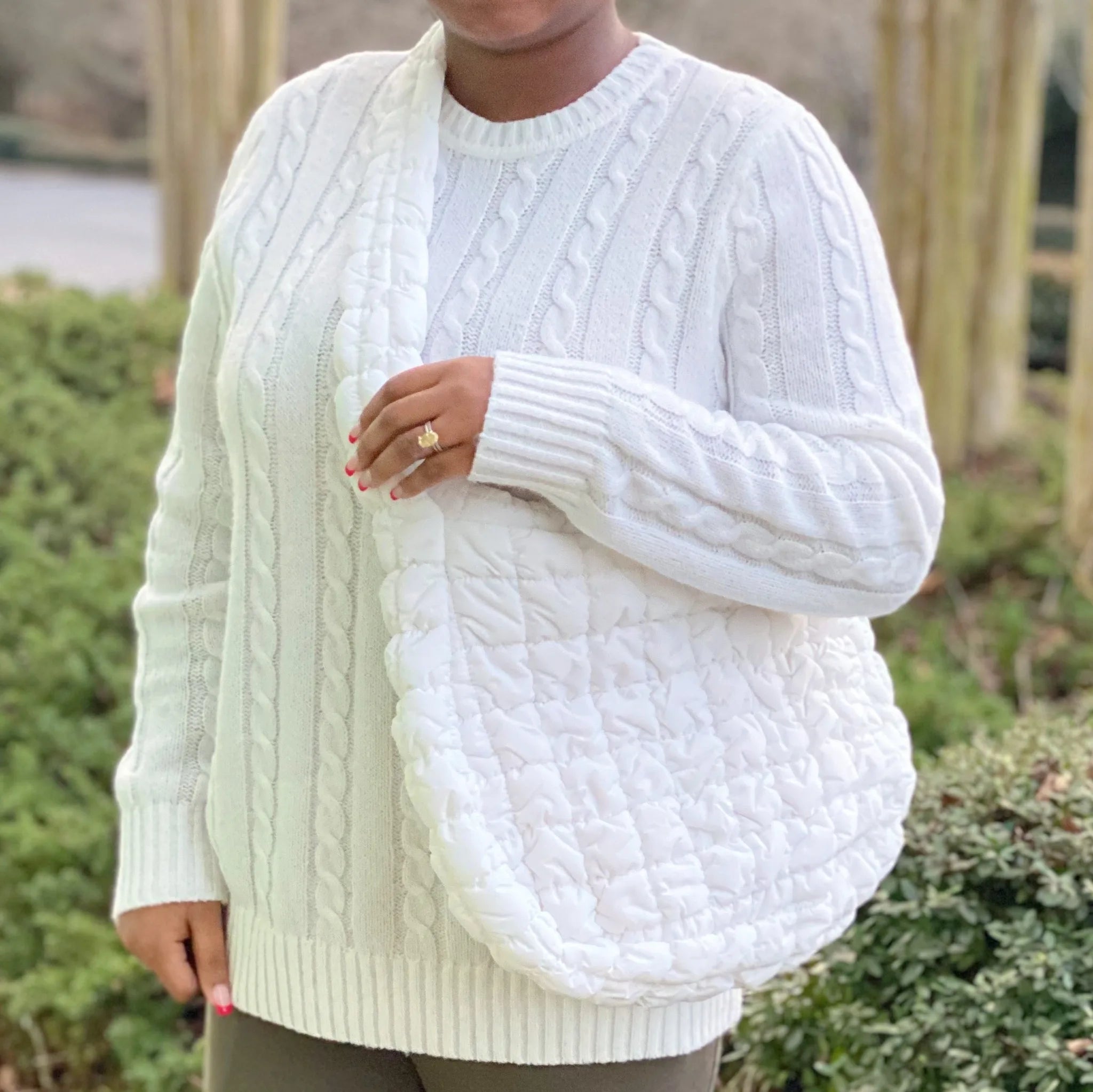 A woman models a Carry All Quilted Cross Body Bag in white, showcasing its soft, textured design in a cozy setting by My Stor