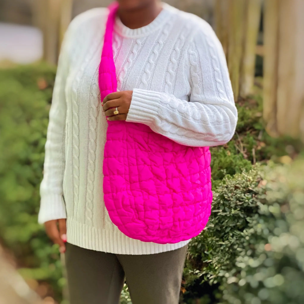 A woman holds a bright pink Carry All Quilted Cross Body Bag while wearing a cozy white sweater, by My Store.
